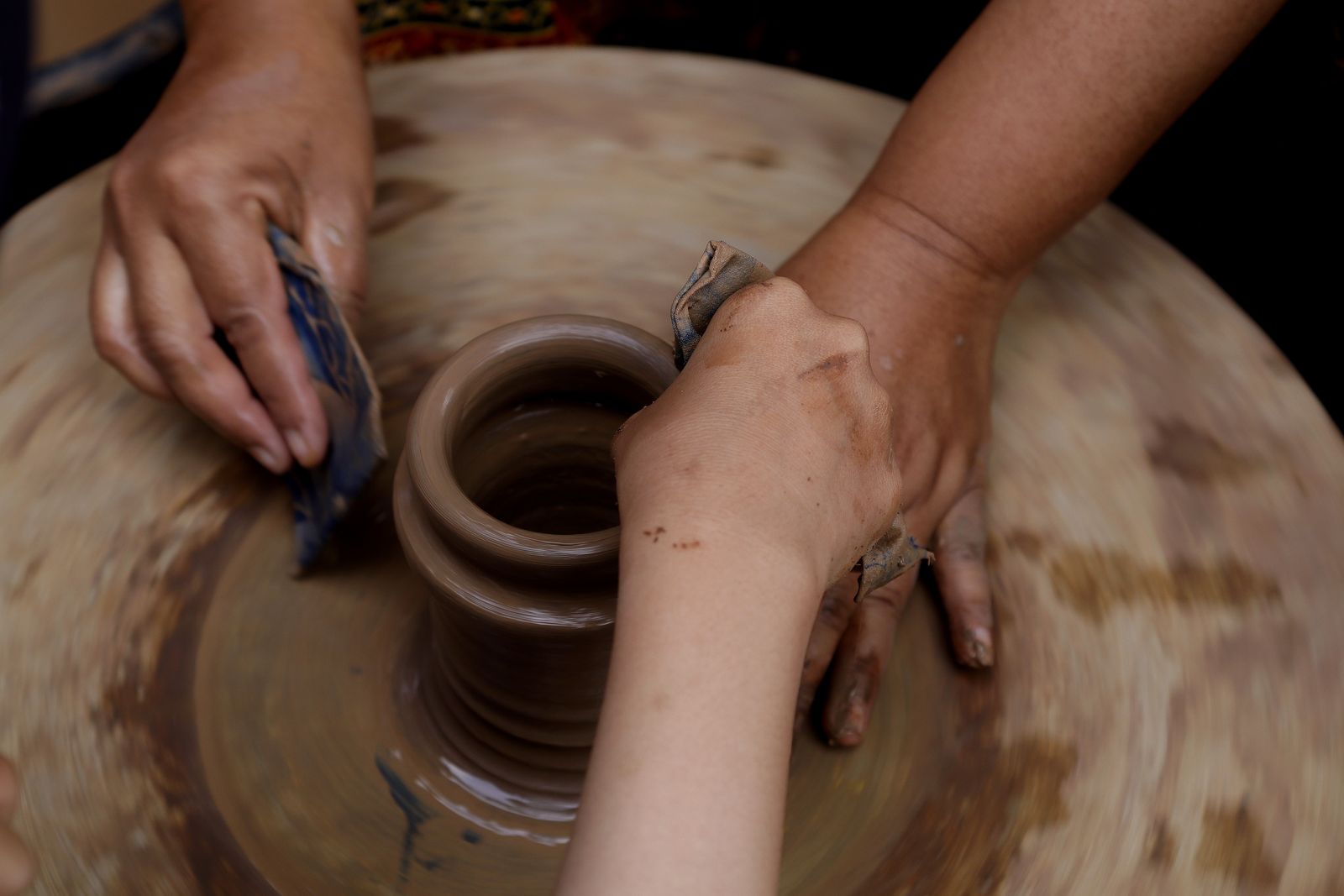 Hands shaping clay on a potter's wheel