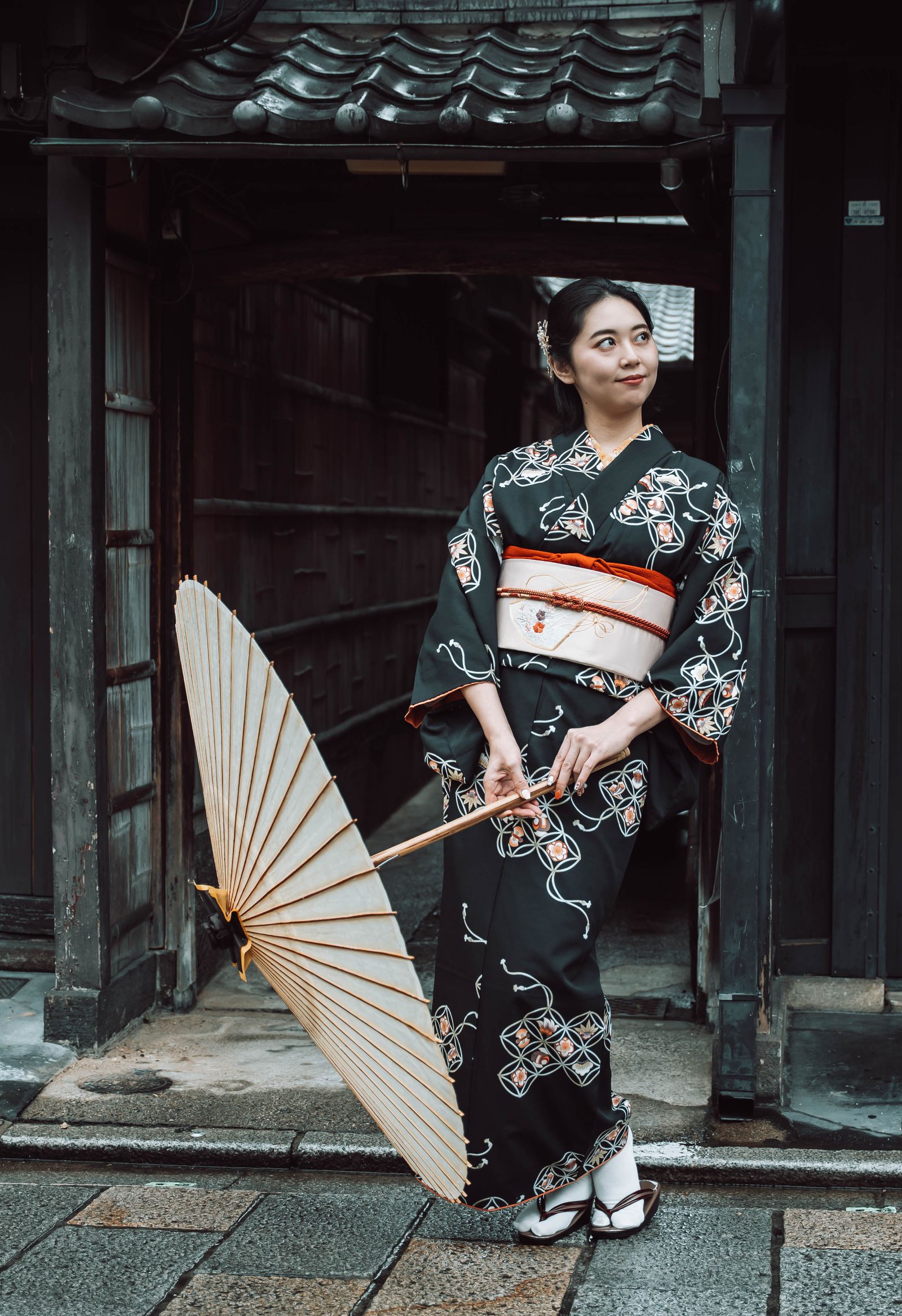 A woman in kimono with a paper umbrella on a Kyoto street